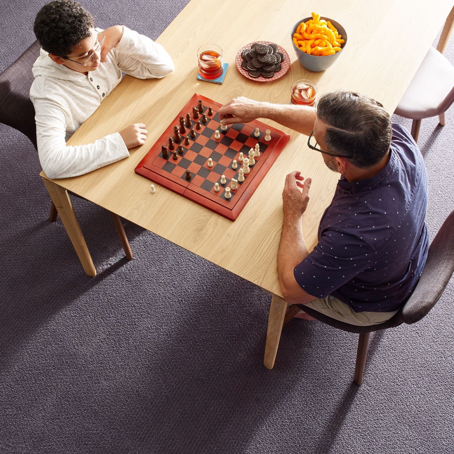 people playing chess at a wooden table in a room with purple carpet from Pritchett's Flooring Design Center in the Colonial Heights, VA area