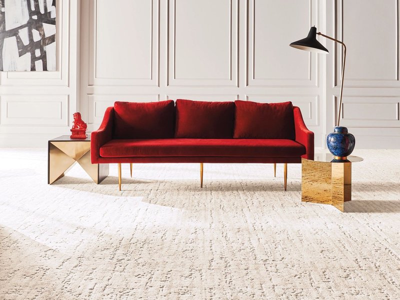 bright living room with a red velvet couch and cream colored textured carpet from Pritchett's Flooring Design Center in the Colonial Heights, VA area